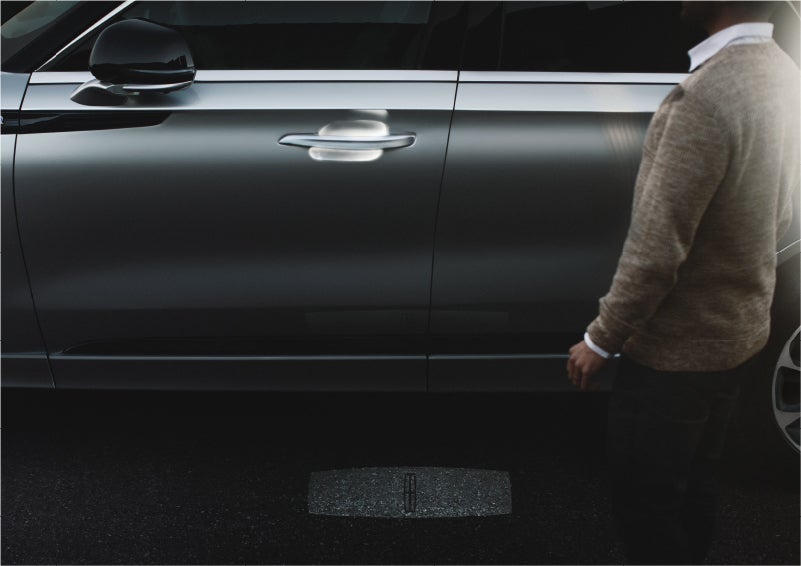 A person approaches a 2023 Lincoln Aviator® Grand Touring SUV as the Lincoln Embrace sequence of welcome lighting illuminates | Mike Carpino Lincoln in Pittsburg KS