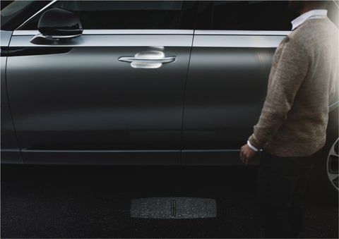 A person approaches a 2023 Lincoln Aviator® Grand Touring SUV as the Lincoln Embrace sequence of welcome lighting illuminates