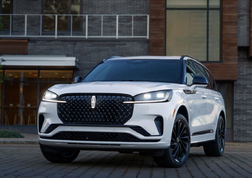 A 2026 Lincoln Aviator® Reserve model is shown with the available Jet Appearance Package parked near a restaurant. | Mike Carpino Lincoln in Pittsburg KS