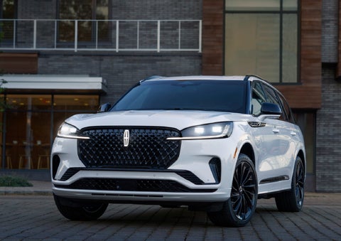 A 2026 Lincoln Aviator® Reserve model is shown with the available Jet Appearance Package parked near a restaurant. | Mike Carpino Lincoln in Pittsburg KS