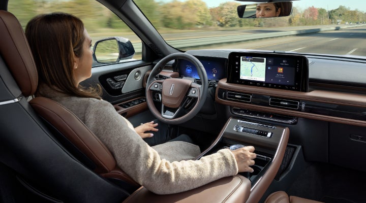 A 2026 Lincoln Aviator® SUV is being driven hands-free on a highway near a forest | Mike Carpino Lincoln in Pittsburg KS