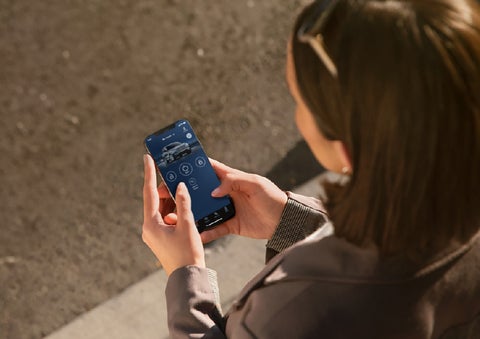 A person is shown interacting with a smartphone to connect to a Lincoln vehicle via the Lincoln Way® app. | Mike Carpino Lincoln in Pittsburg KS