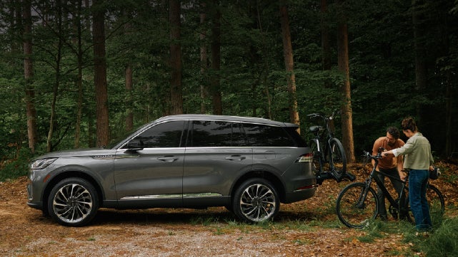 A father and son load e-bikes on a bike rack attached to a 2027 Lincoln Aviator® SUV. | Mike Carpino Lincoln in Pittsburg KS